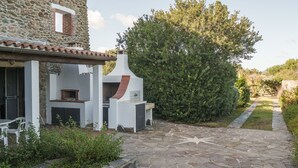 Un edificio de piedra con chimenea, asientos al aire libre y un sendero de piedra que lleva a un arbusto.