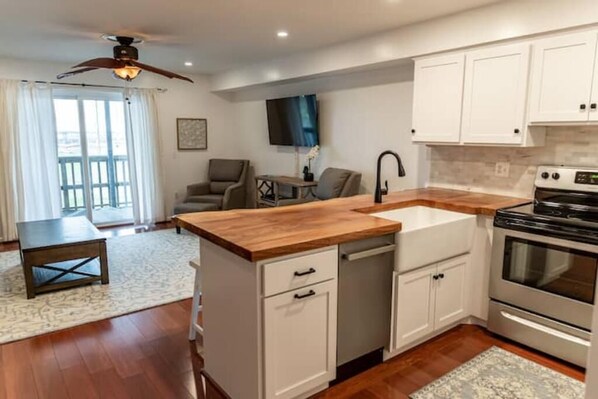 A modern kitchen with white cabinets, a wooden countertop, and a built-in stove.