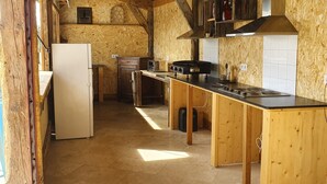 A kitchen with wooden walls, a tiled backsplash, a stove, and a refrigerator.