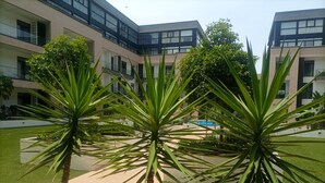 A courtyard with palm trees, a swimming pool, and modern buildings with balconies. -  Embassy Gardens by Morninglife Luxury (Accra)