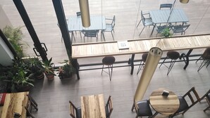 A spacious outdoor seating area with multiple wooden tables and chairs, surrounded by potted plants. -  Embassy Gardens by Morninglife Luxury (Accra)