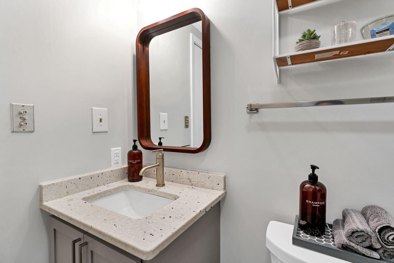 A bathroom with a sink, mirror, towel rack, and toiletries.
