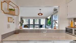 A kitchen with a large island, white cabinetry, and a view of the outdoors through large windows. - Pinehurst 2-bedroom, 2-bath Condo Available for Rent (Pinehurst)
