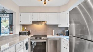 A modern kitchen with white cabinets, stainless steel appliances, a microwave, oven, dishwasher, and a refrigerator. - Pinehurst 2-bedroom, 2-bath Condo Available for Rent (Pinehurst)
