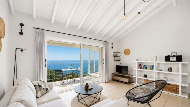 Een moderne woonkamer met een grote schuifpui naar een balkon met uitzicht op zee.