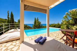 A covered outdoor area with a pool, a table, and a chair.