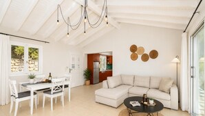 A spacious living area with a dining table, sofa, and a kitchen in the background.