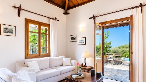 A living room with a sofa, a coffee table, and a view of an outdoor patio with a pool.