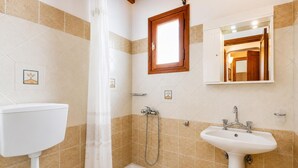 A bathroom with a toilet, shower, and sink.