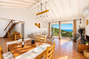 Un vaste espace de vie comprenant une table à manger, un canapé et une vue sur la mer.