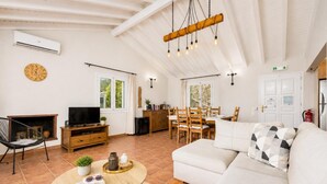 A spacious living area with a sofa, a television, a dining table, and a fireplace. - Villa Gardenia - One Bedroom Villa, Sleeps 2 (Paxi)