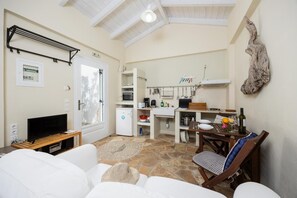 Un espace de vie compact comprenant un coin cuisine, un coin repas et un coin salon avec un téléviseur et un canapé.