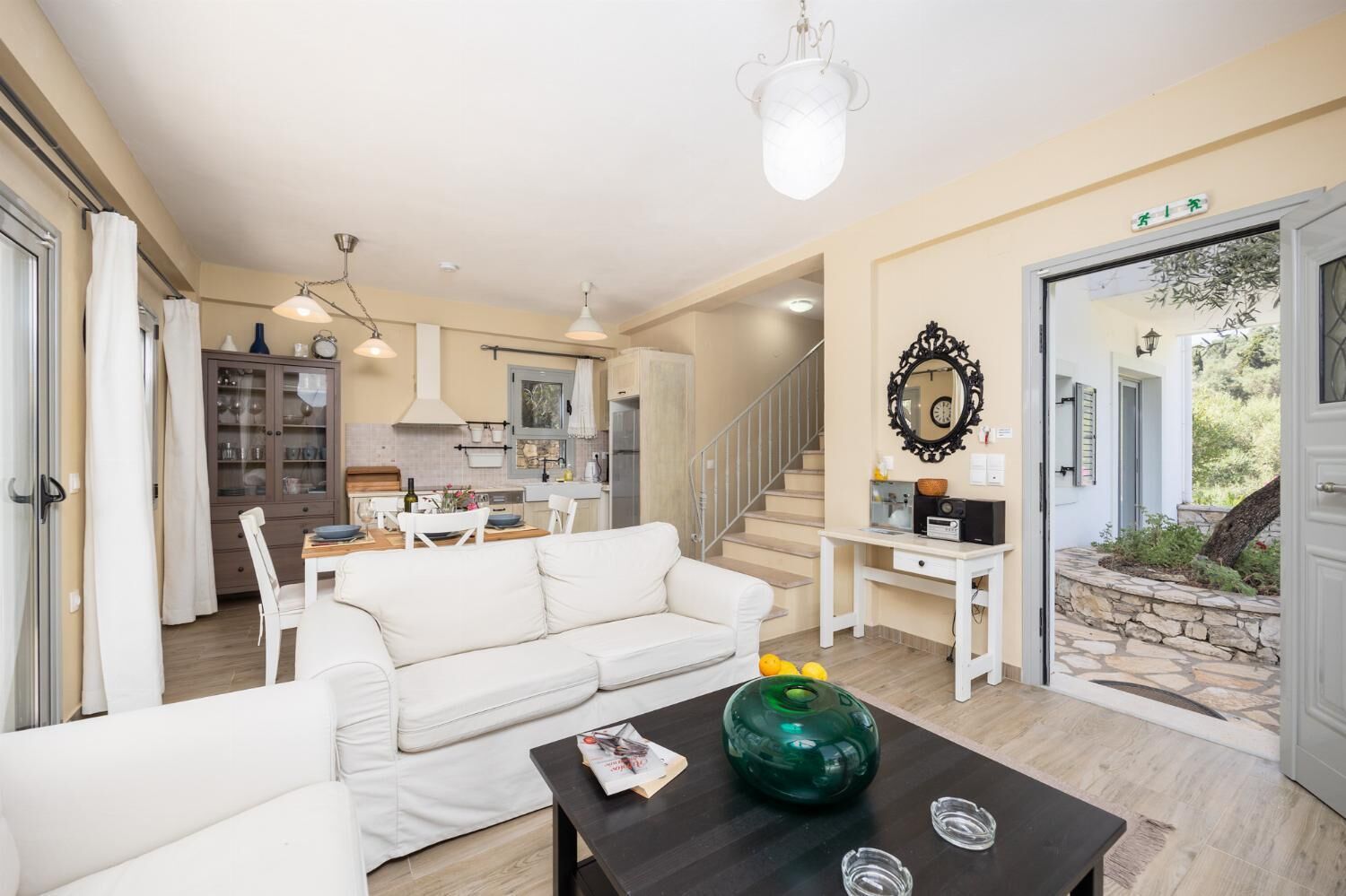 Un espacio habitable amplio con un sofá blanco, una mesa de centro y una cocina al fondo.