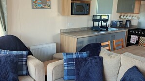 Un espacio de sala cómodo con un sofá y sillones, una cocina con microondas, tostadora y hervidor, y un mapa enmarcado en la pared.