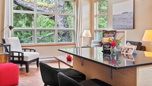 Una habitación de hotel moderna con un ventanal grande, un escritorio, una silla y un sofá.