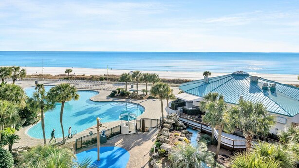 Ein Resort mit großem Pool, Strand und einem Gebäude mit blauem Dach.
