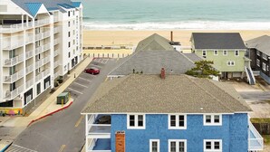 A coastal hotel with multiple floors, a parking lot, and a view of the beach.