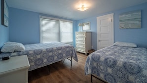 A bedroom with two beds, a dresser, a lamp, and a painting on the wall.