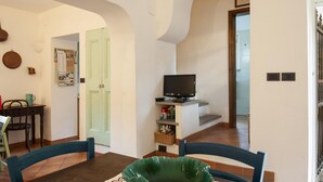 Un comedor con una mesa, sillas y un televisor sobre un soporte.