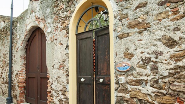 Un edificio de piedra con dos puertas de madera, una de ellas con un pequeño ventanal arriba.
