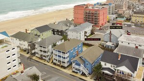 A coastal residential area with a beach view, a parking space, and a building labeled "STAY HERE". - OCHG 6 10th Steet Top (Ocean City)