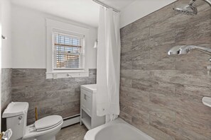 Een badkamer met toilet, wastafel en bad.