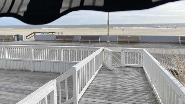 Una pasarela de madera que conduce a una playa con bancos y vistas al océano.