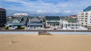 A beachfront hotel with multiple buildings, including a large structure with a balcony and a smaller building with a green roof.