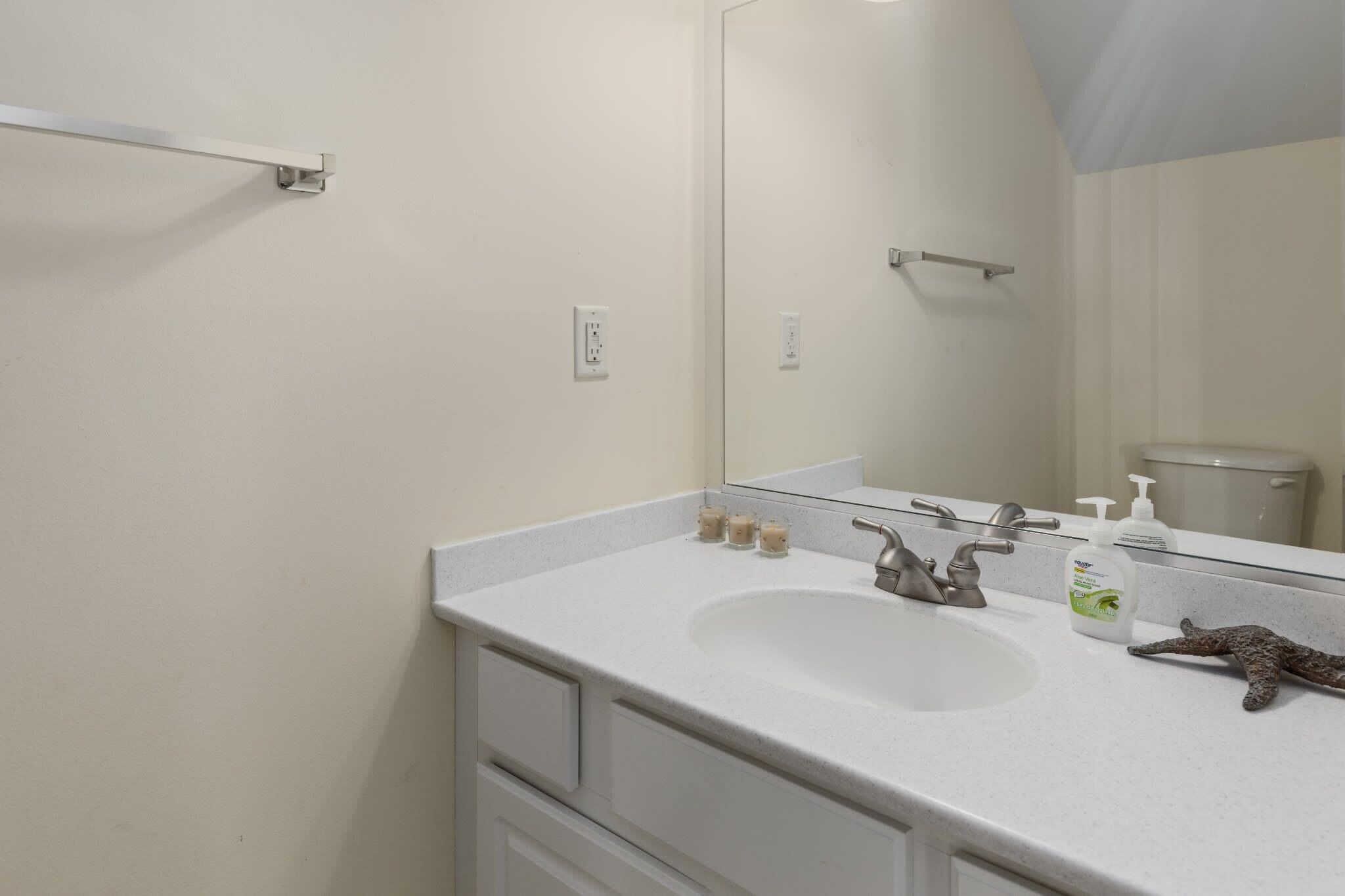 A bathroom with a white sink, mirror, and a towel rack.