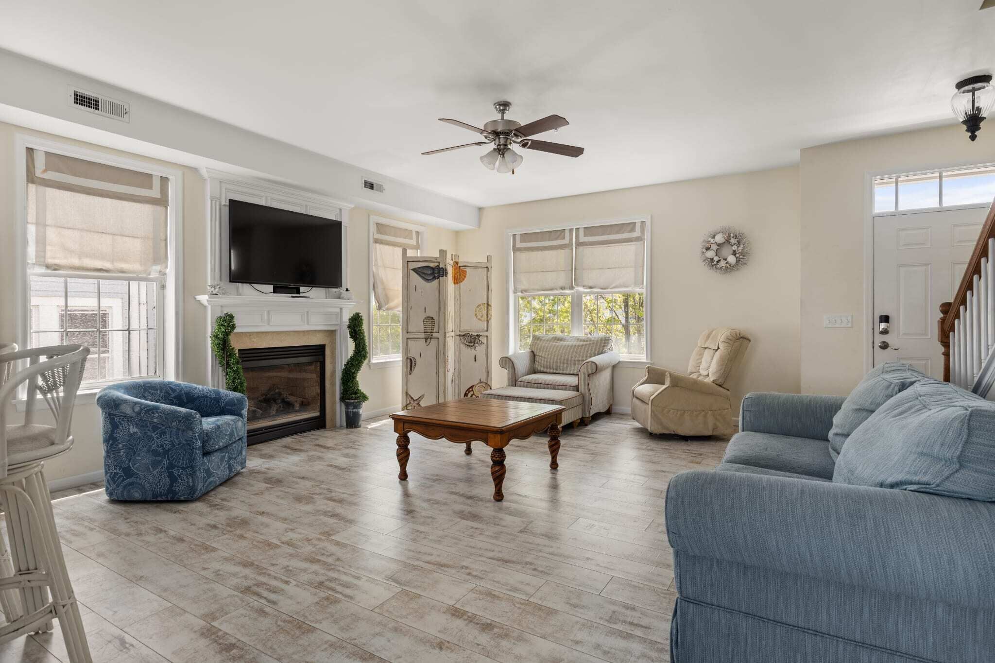 A living room with a fireplace, a television, and a ceiling fan.