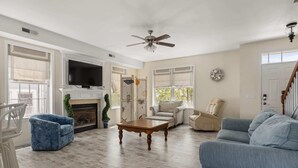 A living room with a fireplace, a television, and a ceiling fan.