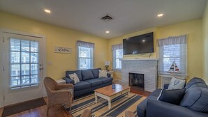 A living room with a sofa, chairs, a coffee table, a fireplace, and a television.