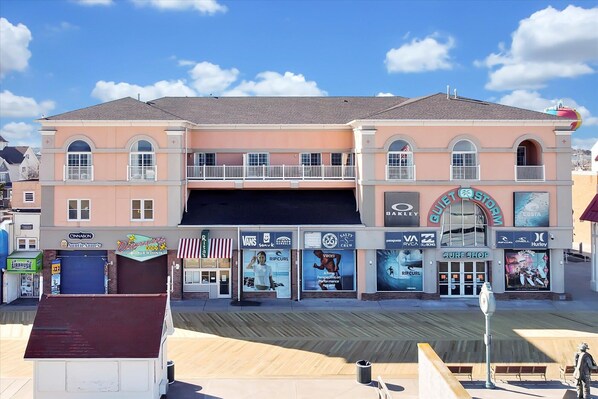 A multi-story building with a surf shop on the ground floor, featuring large posters and a prominent sign.