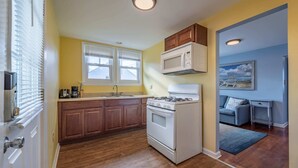 A compact kitchen with wooden cabinets, a white stove, and a microwave.