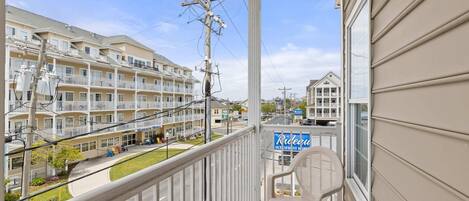 A balcony with a view of a multi-story building, a sign for 'Rideau Oceanfront', and a street with cars and a clear sky.