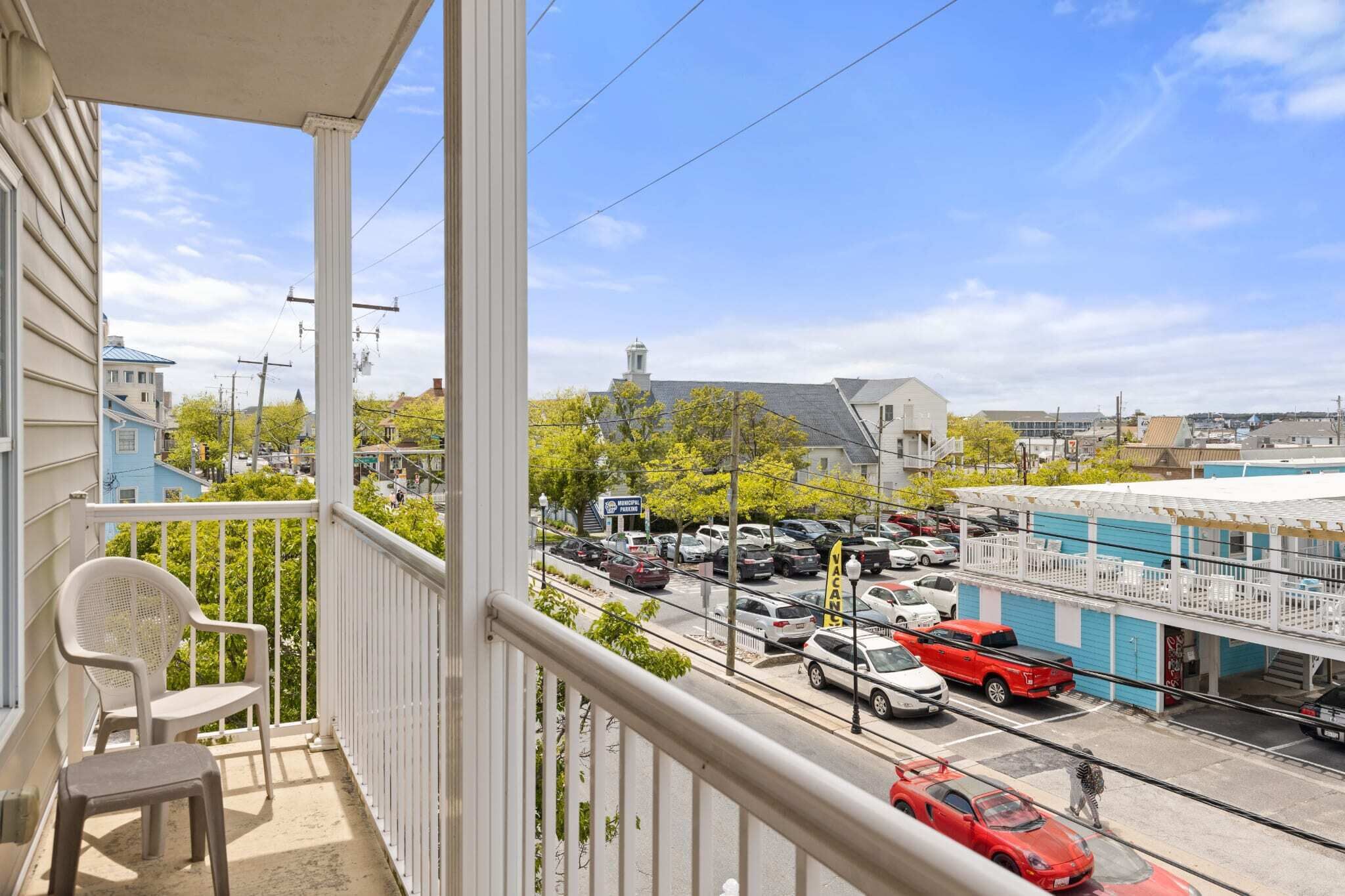Un balcon donnant sur un parking et des immeubles.