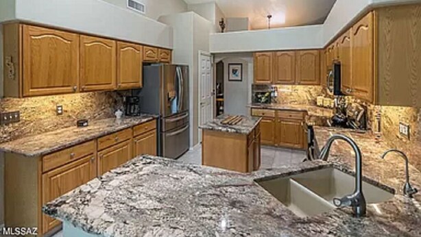 A kitchen with granite countertops, wooden cabinets, and stainless steel appliances.