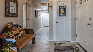 A hallway with a bench, a welcome sign, and a door.
