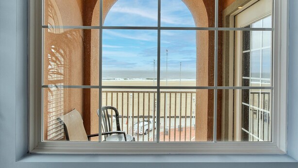 A balcony with a view of the beach, featuring a railing and a chair. - OCHG Oceanfront Villa 2 (Ocean City)