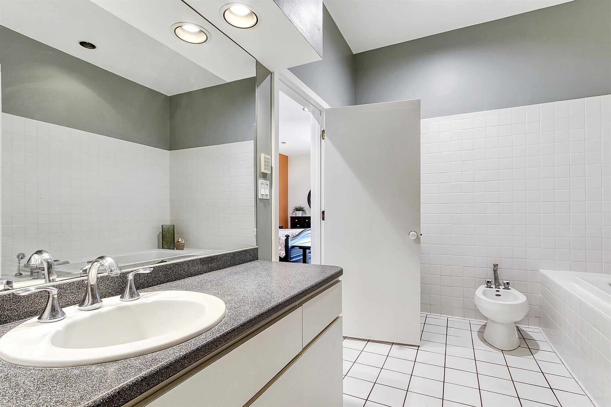 A modern bathroom with a white sink, a bidet, and a bathtub.