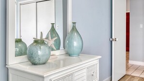 A white vanity with a mirror above it, displaying three ceramic vases and a starfish decoration. - OCHG Oceanfront Villa 2 (Ocean City)