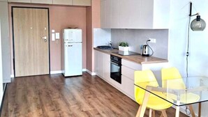 Eine moderne Küche mit Holzboden, weißen Schränken, einem eingebauten Backofen und einem Glastisch mit gelben Stühlen.