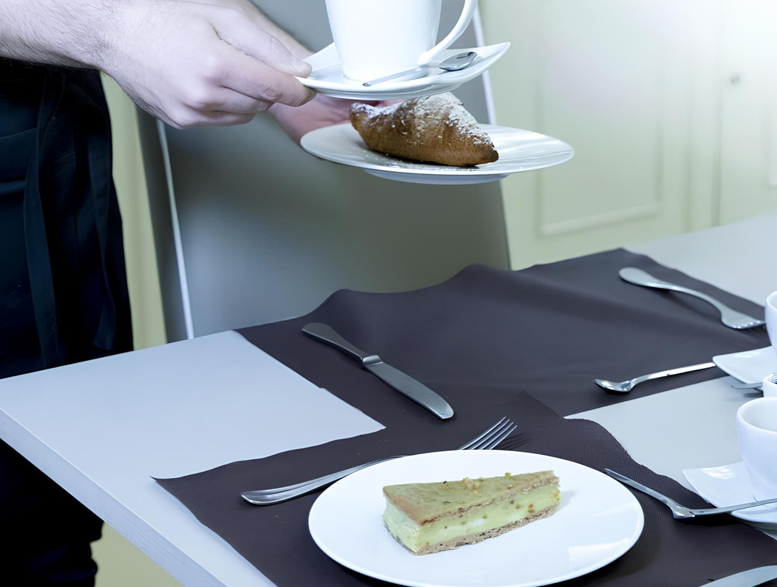 Una persona sirve una porción de pastel en un plato blanco, con un pastelito en un plato aparte.
