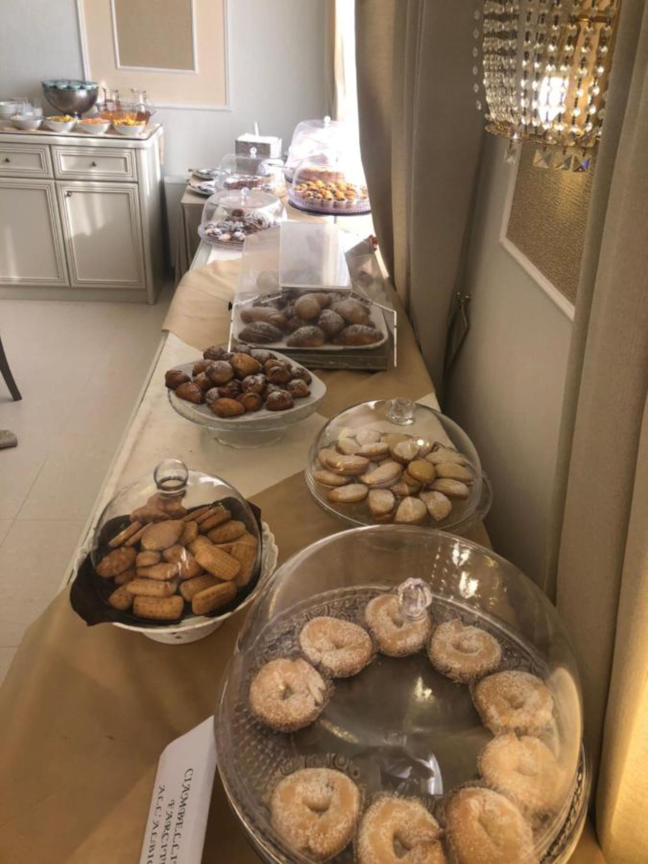 A buffet table with various pastries and desserts covered in glass domes.