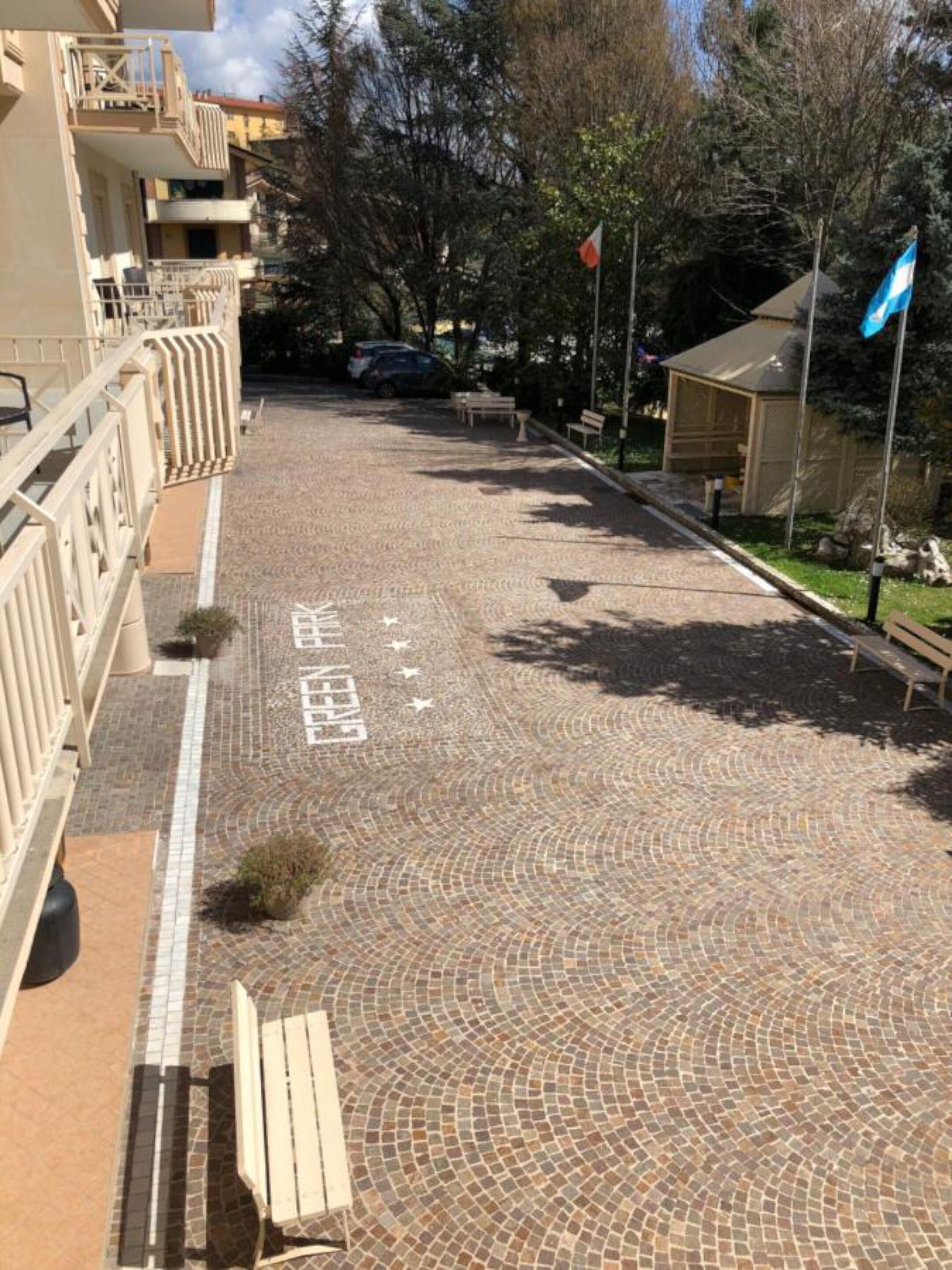 A paved courtyard with a circular pattern, benches, and a flagpole with a flag.