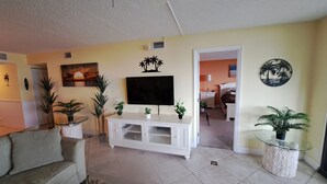 A living room with a sofa, TV, and decorative plants. - PALMS OF BAY BEACH-UNIT 1G

EXCEPTIONAL CORNER UNIT ON THE BAY WITH LARGE LANAI (Fort Myers Beach)