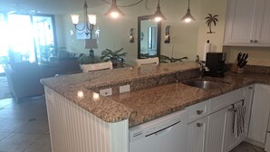 A kitchen with granite countertops, white cabinetry, a built-in dishwasher, and pendant lighting. - PALMS OF BAY BEACH-UNIT 1G

EXCEPTIONAL CORNER UNIT ON THE BAY WITH LARGE LANAI (Fort Myers Beach)