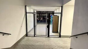Eine Treppe führt zu einem verschlossenen Eingang mit einem Metallgitter und einem vertikal gestreiften Wandmuster.