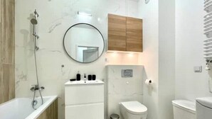 Ein modernes Badezimmer mit einer Badewanne, einer Toilette, einem Waschbecken und einem Spiegel.
