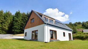 A modern two-story house with a sloped roof, large windows, and a well-maintained lawn. - Glen View Lodge (Inverness)